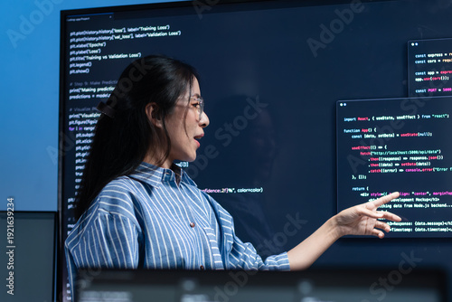 Cuadro en lienzo Professional Female Programmer presenting code on the screen and discussing and brainstorming with team while project meeting session in office