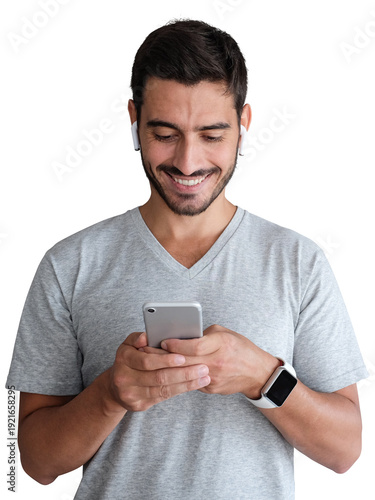 Young man in grey t-shirt smiling while using smartphone with earbuds and smartwatch