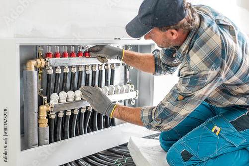 The worker's hands adjusts and checks valves of a underfloor heating distributor. Underfloor heating.