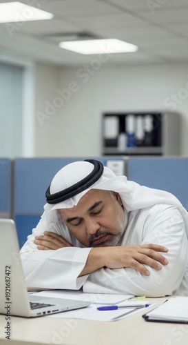 Middle-aged Arab businessman sleeping at office desk due to Ramadan fasting fatigue and burnout