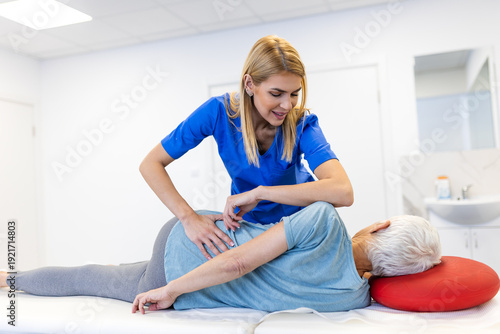 Tableau sur toile Professional female therapist performing deep tissue massage on the lower back of a senior woman
