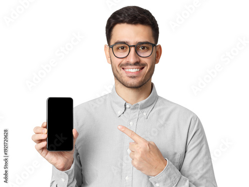 Smiling young man in grey shirt and glasses pointing at blank smartphone screen, portrait