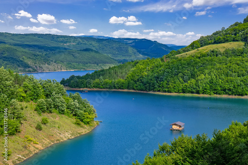 Panoramic landscape of Lake Zavoj surrounded by forested hills and mountains near Pirot in southeastern Serbia under blue sky