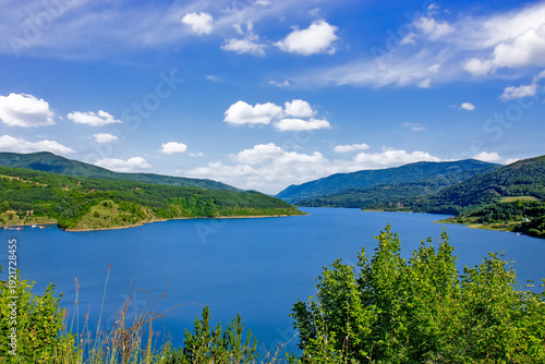 Panoramic landscape of Lake Zavoj surrounded by forested hills and mountains near Pirot in southeastern Serbia under blue sky