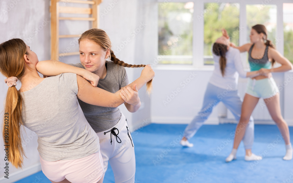 Fototapeta premium Girl and woman athletes practice self-defense wrestling. Training at Academy of Martial Arts martial arts hand-to-hand combat.