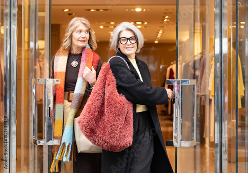 Φωτογραφία Two smiling mature women exiting a modern boutique store after shopping