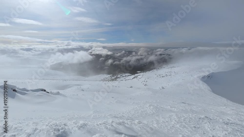 Wallpaper Mural Snow-covered mountain landscape under cloudy sky with rolling clouds and distant forested slopes Torontodigital.ca