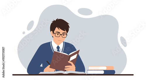 Young man wearing glasses reading a book at a desk.