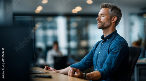 Faceless businessman meditating in lotus position at office desk with defocused colleagues blurred in background, showcasing mindfulness and stress management in workplace, with