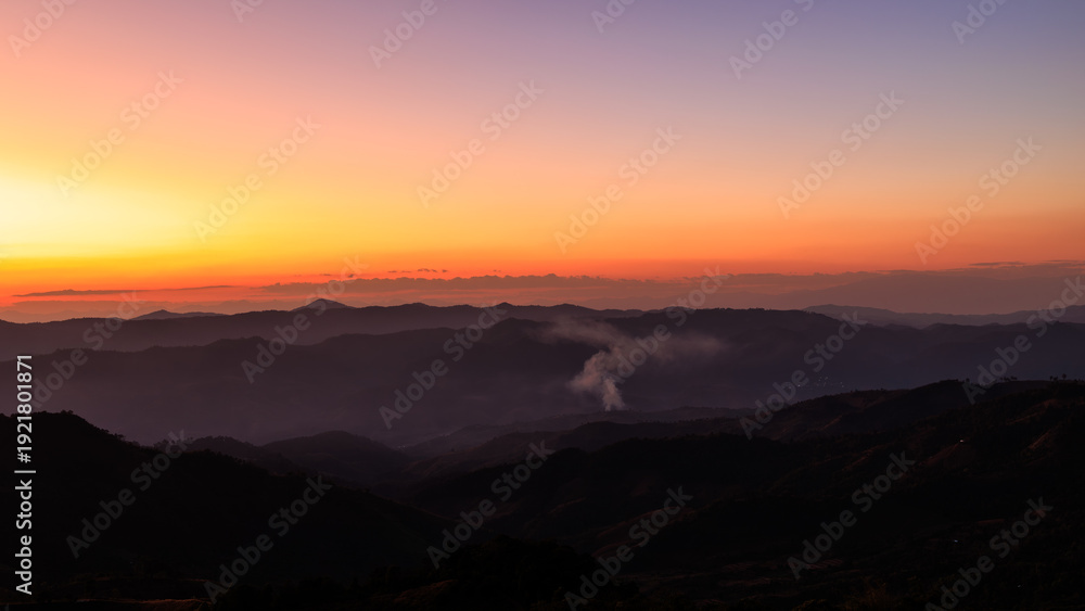 Obraz premium Majestic Sunset Gradient Sky Over Silhouetted Mountain Ranges With Fog And Smoke