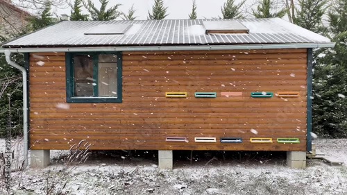 Wooden beehives in winter garden during heavy snowfall with snowflakes