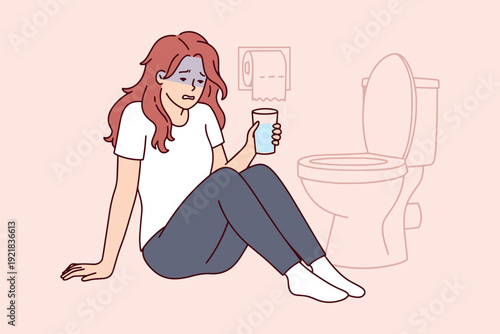 Young woman feeling sick next to toilet with water glass. Concept of early pregnancy symptoms, morning sickness, or alcohol hangover. Nausea and vomiting health issues.
