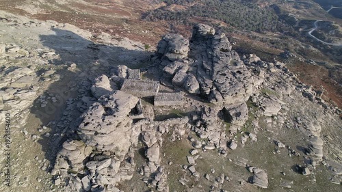4K aerial drone footage performing a smooth circular orbit around the mysterious Drakospita (Dragon Houses) on the summit of Mount Ochi. The ancient megalithic stone structures stand against a rugged 
