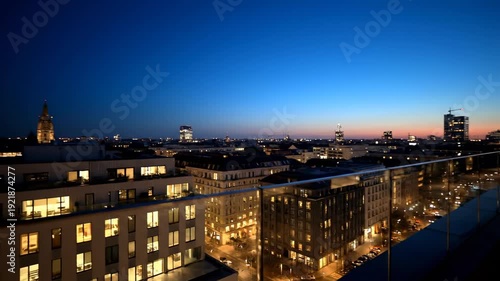 Stunning Nighttime Cityscape View from a High-Rise Balcony with Illuminated Buildings and a Vibrant Sky.