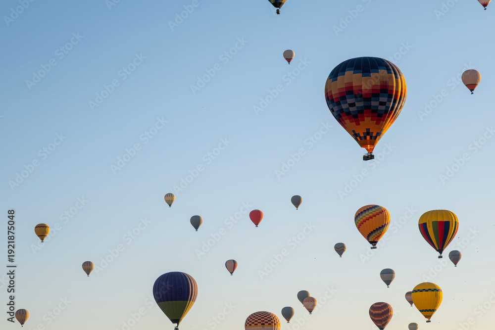 Obraz premium Colorful Hot Air Balloons Flying in Blue Sky. Hot Air Balloon Tour Under Clear Blue Sky. Adventure Travel with Hot Air Balloons. Tourism Concept – Hot Air Balloons in Open Sky.