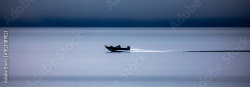 Two people in a fishing boat driving on Chequamegon Bay, on Lake Superior off of Washburn, Wisconsin in September