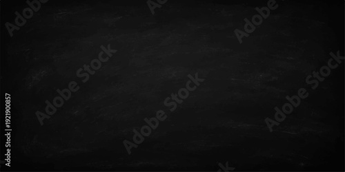 A dark vintage black and white chalk board with a rough grunge texture and aged gray stone surface makes a blank dirty chalkboard wallpaper backdrop for a textured design frame