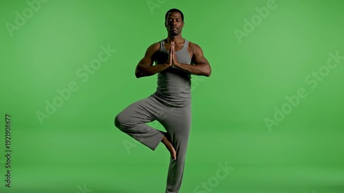 Man Practicing Yoga in Gray Outfit Against Green Background