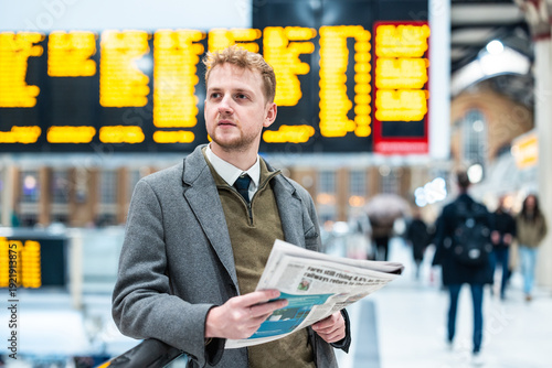 Employee holding newspaper waiting for train at station