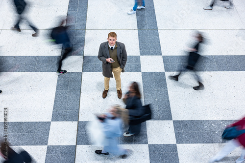 Businessman standing still in busy urban crowd