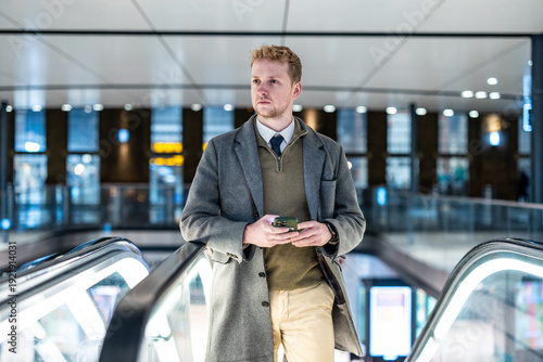 Tableau sur toile Young professional man using phone on escalator