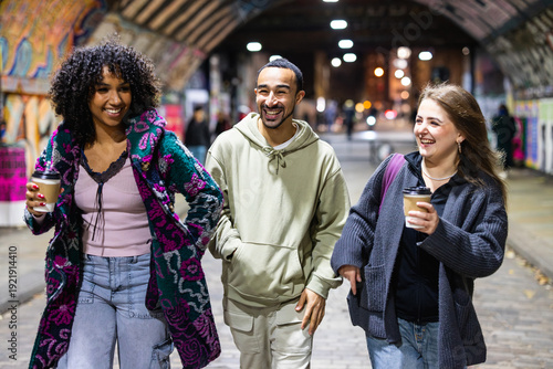 Diverse friends laughing walking in urban tunnel at night