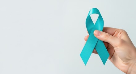 A hand holding a teal awareness ribbon symbolizing support for various health issues.