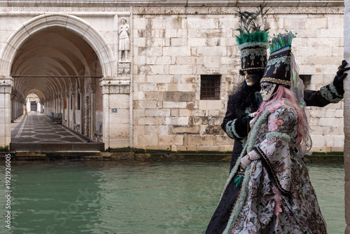 Elegant Masked Couple in Period Costumes by the Canal During Venice Carnival