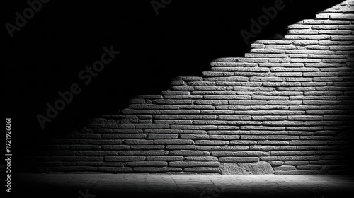 Textured stone brick wall illuminated by a stark spotlight casting deep shadows above