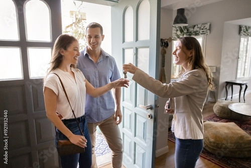 Photos Realtor handing over house key to happy couple standing in residential doorway