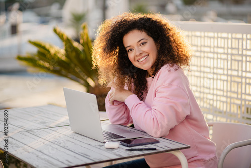 woman sitting in summer cafe working on laptop