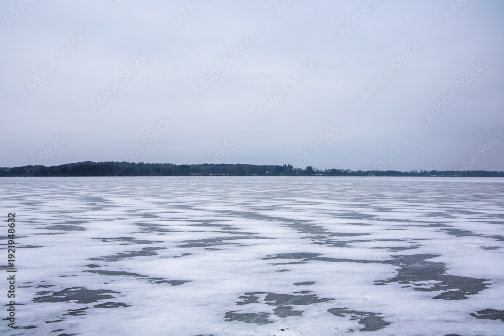 Obraz premium Frozen lake ice and snow covering winter landscape