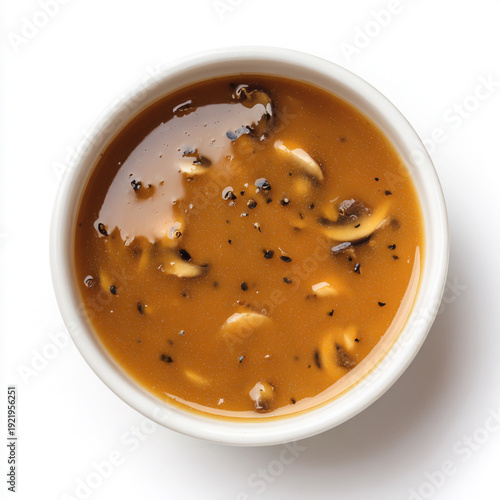 Top shot of a bowl filled with light brown hunter sauce with small champignon pieces and fine black pepper in the sauce