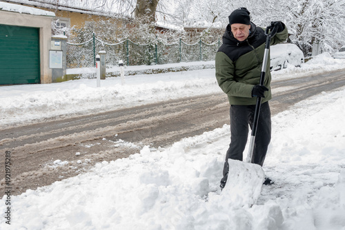 Canvastavla person clears pedestrian passage along road in snowy cold weather