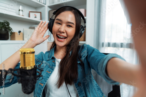 Konstfotografi Host channel young beautiful Asian girl making selfie with smartphone wearing headphones at modern studio home office concept of behind the scene broadcaster live streaming on social media