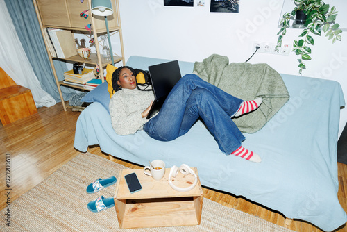 Woman at home chilling on couch using laptop.. Direct flash
