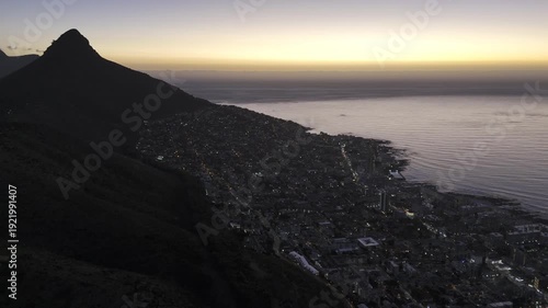 Drone orbits to the left from view of Lion's Head as camera pans from Sea Point to Green Point after sunset in Cape Town, South Africa