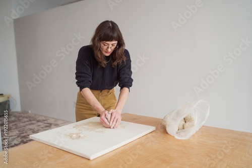 Woman kneading clay on worktable  
