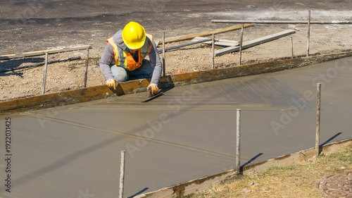 A worker is jet patching asphaltwith a flat finishing trowel is finishing sidewalk level