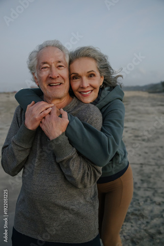 Happy Elderly Couple Smiling and Embracing on a Scenic Beach Walk