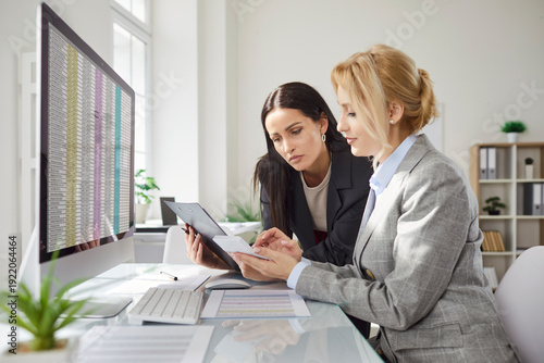 Young business people company employees having discussion about financial data analyzing company accounting on meeting. Woman accountant working on pc with charts and talking with colleague.
