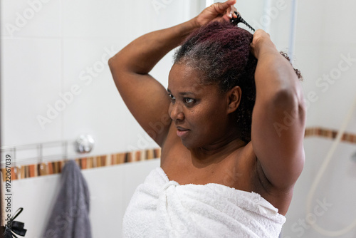 a woman in the shower smiling and combing her hair