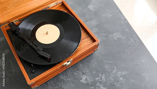 A vintage wooden record player sits on a gray surface with a vinyl record in place and the tonearm lowered. Soft light enters from the side