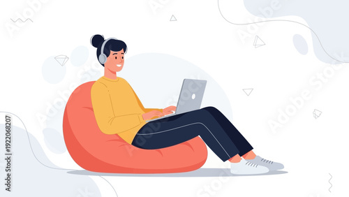 Young person with headphones using laptop on bean bag chair, relaxed remote work or study