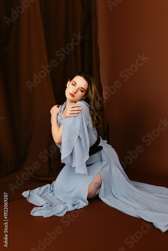 Woman in elegant draped gown posing thoughtfully