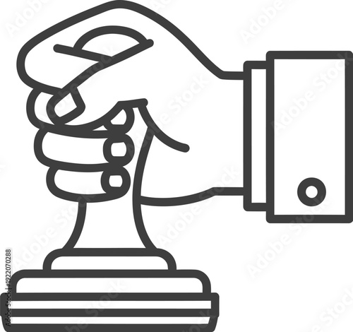 Hand in business cuff presses down firmly on a traditional rubber stamp device to finalize an important document or process.