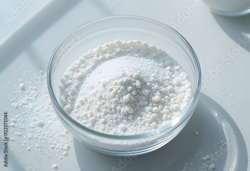 A bowl filled with granulated sugar on a clean surface. citric acid powder