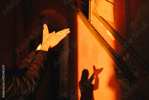 Hands creating a bird shadow on an orange wall