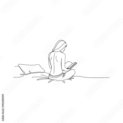 Woman sitting comfortably reading a book with pillow on floor