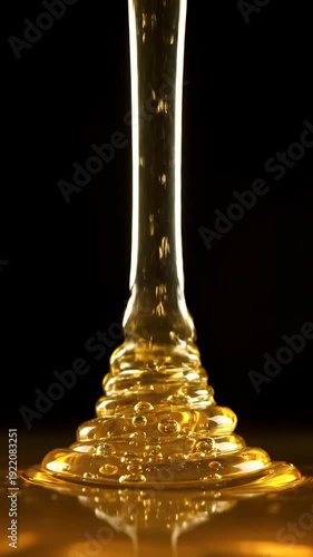 Golden Honey Drips Onto a Reflective Surface With Bubbles Against a Stark Black Background in Dramatic Studio Lighting